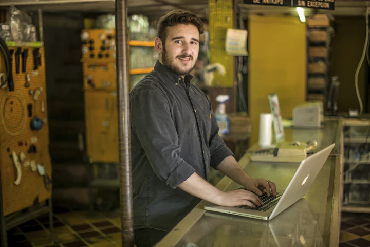 A smiling technician using a laptop in a workshop